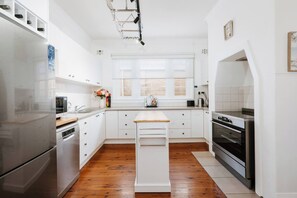 Une cuisine moderne avec des meubles blancs, un plan de travail en bois et des appareils électroménagers en acier inoxydable.