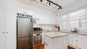 Cocina moderna con muebles blancos, electrodomésticos de acero inoxidable y una isla de madera.
