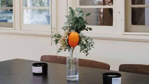 Una mesa de comedor con dos velas y un florero con arreglo floral.