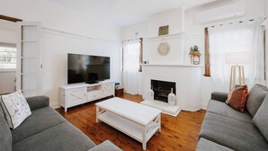 Una sala de estar con televisor, chimenea y dos sofás.