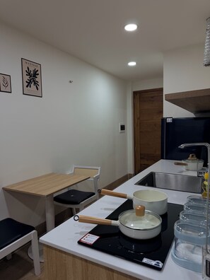 Una cocina compacta con comedor, estufa, pileta y refrigerador.