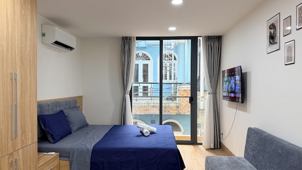Quarto com cama, televisão, guarda-roupa e varanda com vista para edifícios.