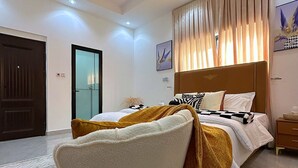 Ein modernes Schlafzimmer mit Bett, Deckenventilator, Stuhl und Nachttisch.