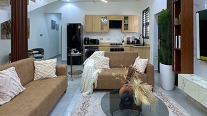 Ein modernes Wohnzimmer mit einer Couch, einem Couchtisch und einer Küche im Hintergrund.