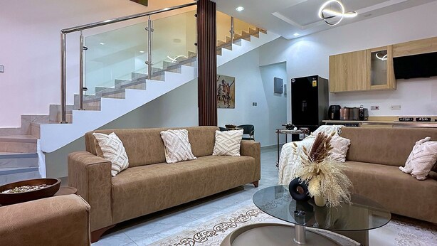 Ein modernes Wohnzimmer mit einer Glaskonstruktion als Treppe, einer Küchenzeile und einem Essbereich.