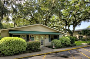 A building with a green awning, a sign reading "Island Housekeepers," and a parking lot with yellow lines. - A Bit of Hope Island Townhouse, Close to Beach and Community Pool (Saint Simons Island)