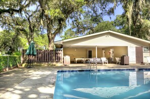 A pool area with a covered patio, outdoor furniture, and a wooden fence. - A Bit of Hope Island Townhouse, Close to Beach and Community Pool (Saint Simons Island)