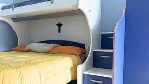 A bunk bed with a yellow bedspread, orange pillows, and a cross on the wall. - PP08 - Porto Potenza, two-room apartment with garden, 100 meters from the sea (Potenza Picena)