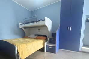 Un lit superposé avec une couvre-lit jaune, une armoire bleue et une horloge au mur.