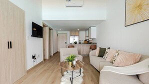 A modern living room with a sofa, a coffee table, and a TV. - Tropical Escape! Breezy Lagoon + Pool Views (Punta Cana)