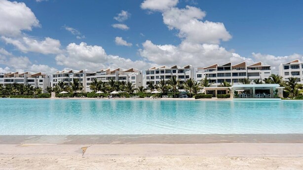 A resort with a large pool, multiple hotel buildings, and palm trees. - Tropical Escape! Breezy Lagoon + Pool Views (Punta Cana)