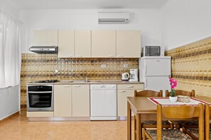 Une cuisine compacte équipée d’une cuisinière, d’un four, d’un lave-vaisselle, d’un four à micro-ondes et d’un petit réfrigérateur.