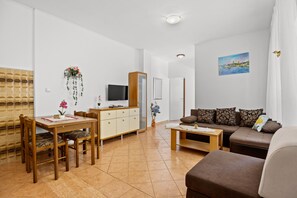 Un salon moderne comprenant un coin repas, un ensemble de canapés, un téléviseur et un tableau accroché au mur.