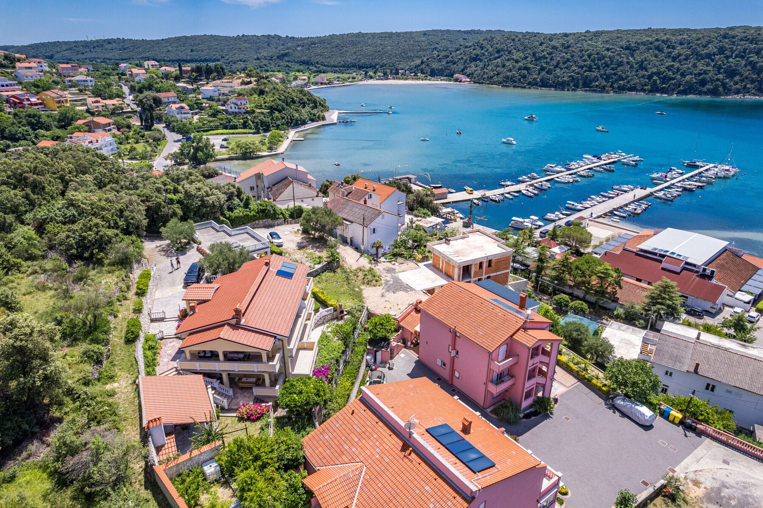 An aerial view of a coastal town with residential buildings, a marina, and boats.