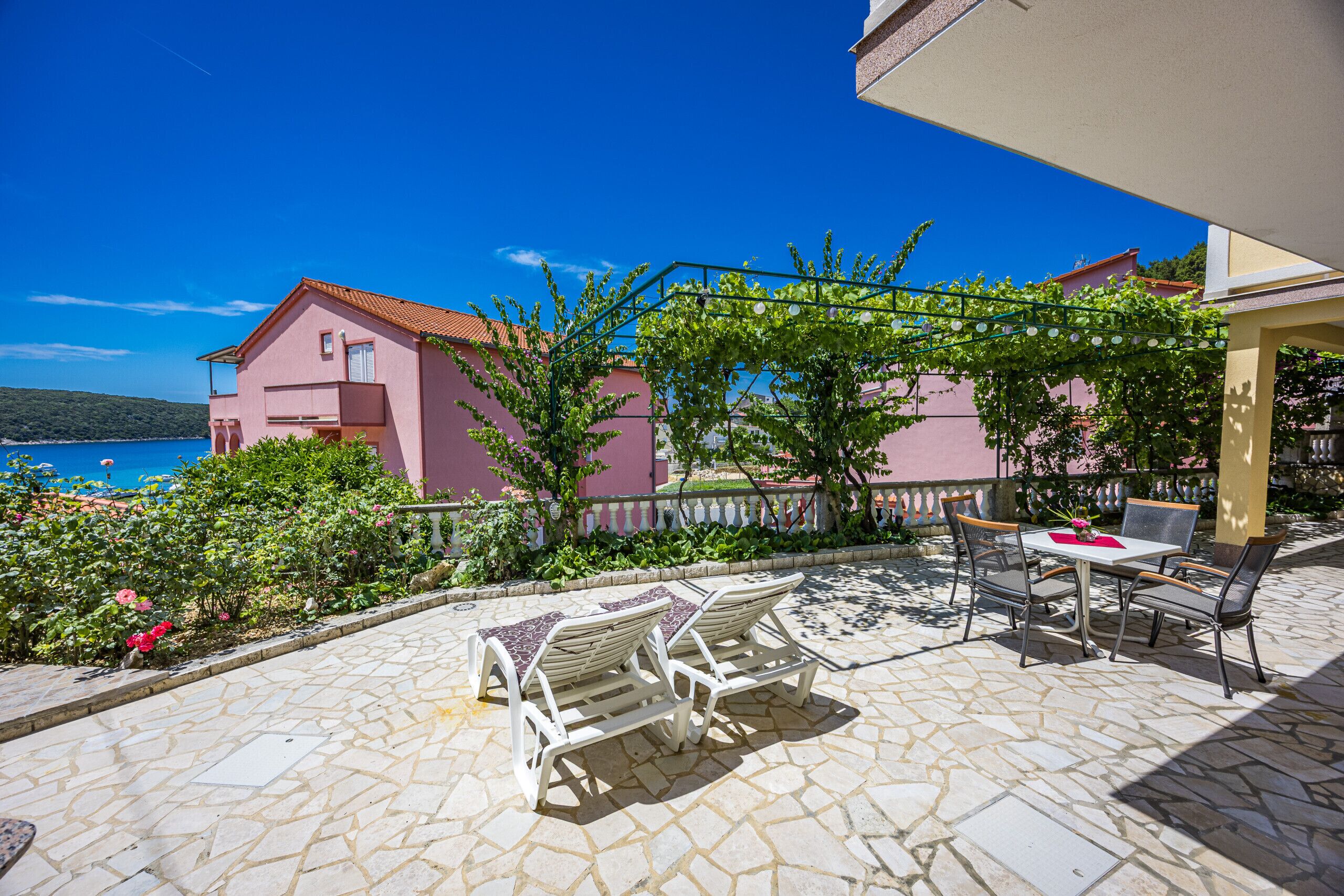 A patio with stone flooring, a table, and two lounge chairs.