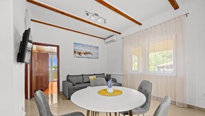 A modern living room with a round dining table, grey sofas, and a painting on the wall. - Two Bedroom Apt near the Beach - Villa Jagoda (Kampor)