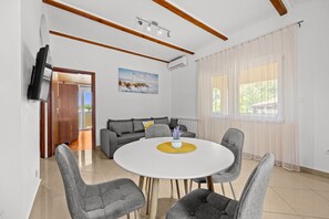 Ein modernes Wohnzimmer mit einem runden Esstisch, grauen Sofas und einem Gemälde an der Wand.
