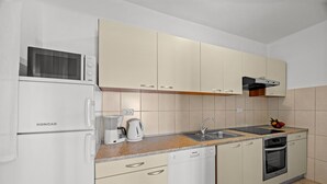 A kitchenette with a white refrigerator, microwave, coffee maker, kettle, sink, and oven. - Four Bedroom Apt. near the Beach - Villa Jagoda (Kampor)