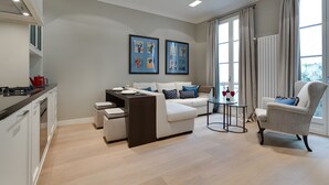 Ein modernes Wohnzimmer mit Sofa, Sessel, Esstisch und Küchenzeile.