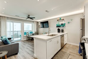 Une cuisine moderne dotée d’un îlot central, d’un lave-vaisselle encastré et d’un téléviseur à écran plat fixé au-dessus de l’îlot.