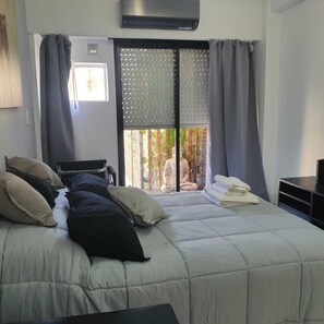 Ein Schlafzimmer mit Bett, Schreibtisch und Blick auf eine Statue durch ein Fenster.