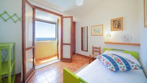 Una camera da letto con un letto, una sedia, una scrivania, uno specchio e un balcone con vista.