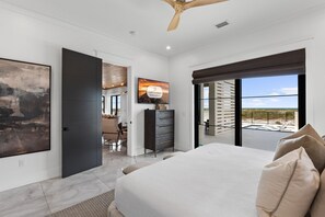 Ein Schlafzimmer mit einem Bett, einem Schminktisch, einem Fernseher und einem Balkon mit Blick.
