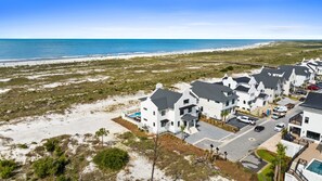 A coastal residential area with modern houses, a beach, and a clear sky. - Rumor Has It: Beachfront, Private Pool, Pet Friendly, Golf Cart Community (Mexico Beach)