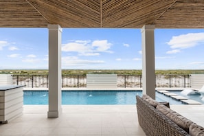 A pool area with a view of the beach, covered by a thatched roof, and a seating area with a view of the pool. - Rumor Has It: Beachfront, Private Pool, Pet Friendly, Golf Cart Community (Mexico Beach)