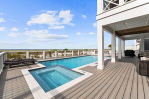 A poolside area with a view of the ocean, a deck with lounge chairs, and a covered seating area. - Shuck Yeah!: Beachfront home with Private Pool located in Sugar Sands community! (Mexico Beach)