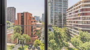 Une vue depuis une fenêtre d’un immeuble de grande hauteur, doté de nombreux étages, de grandes fenêtres et présentant un mélange de styles architecturaux modernes et plus anciens.