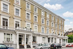 A multi-story residential building with a symmetrical facade, white-framed windows, and a brick exterior. - Cozy City Two Double Bedroom Apartment in Chelsea (London)