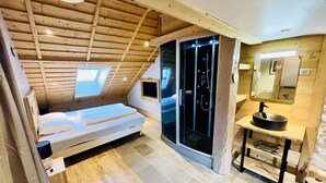 Een slaapkamer met dakraam, een schuifdeur naar een badkamer en een houten plafond.