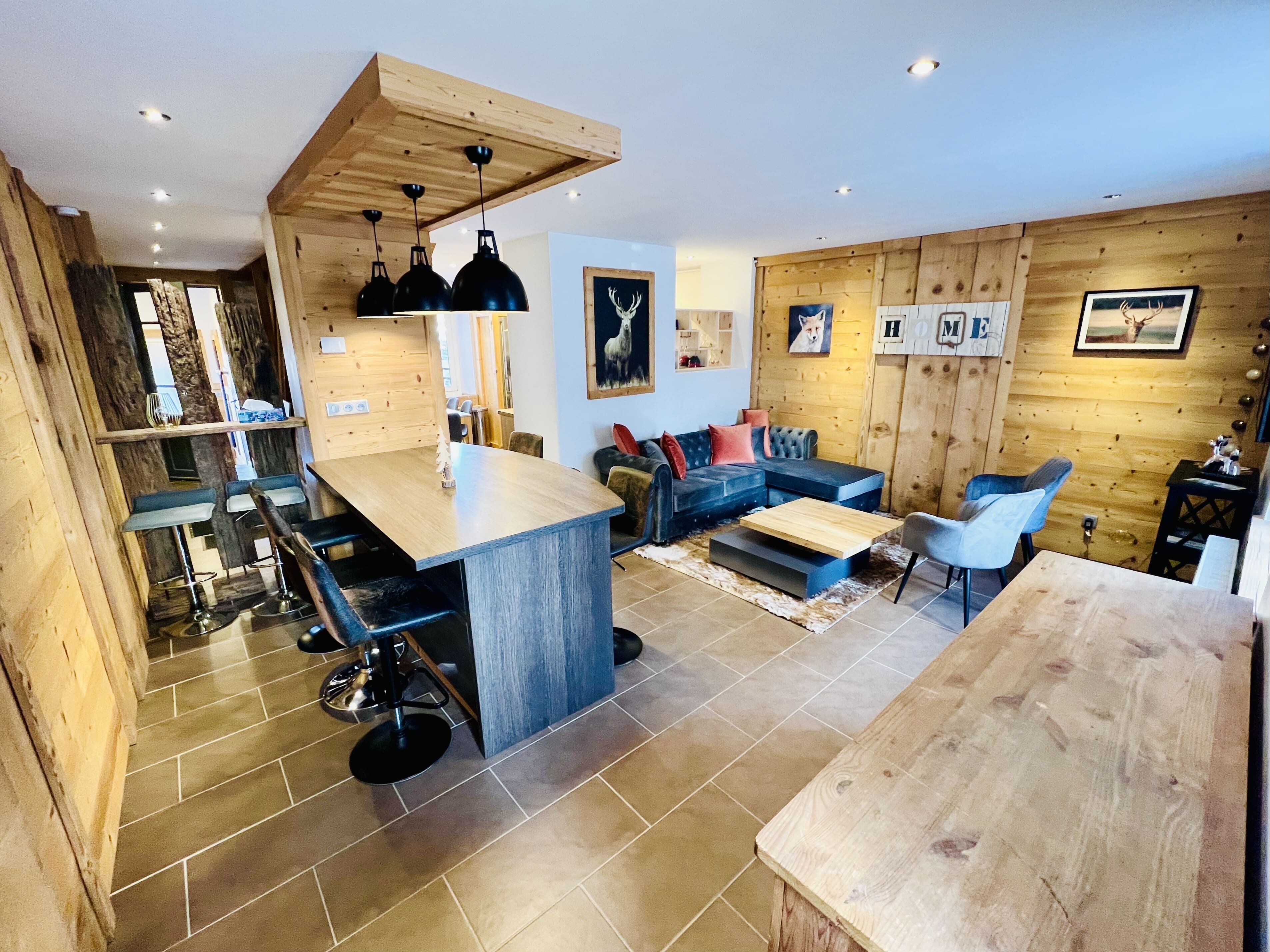 A modern interior with a kitchen, dining area, and living room, featuring wooden walls, a central island, and contemporary furniture.