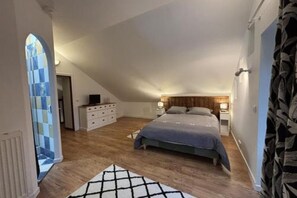Un dormitorio con una cama grande, un aparador y una mesita de noche.