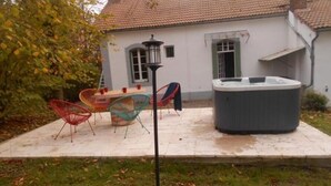 Eine Terrasse mit Whirlpool, Sitzgelegenheit und einer Laterne.