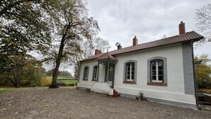 Ein eingeschossiges Haus mit Schotterauffahrt und einem Baum im Vordergrund.