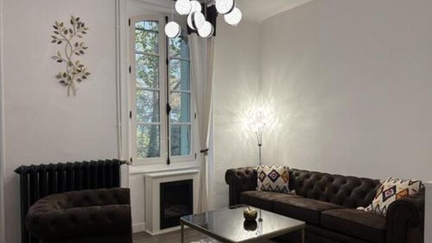 Ein Wohnzimmer mit einer Couch, einem Couchtisch, einem Kamin und einem Fenster mit Vorhängen.