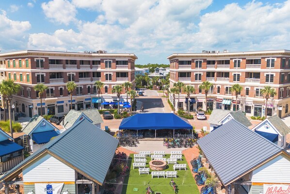 A courtyard with a blue canopy, surrounded by brick buildings with balconies, palm trees, and bicycles. - Dont Worry Beach Happy, Welcome to your perfect 30A getaway! (Inlet)