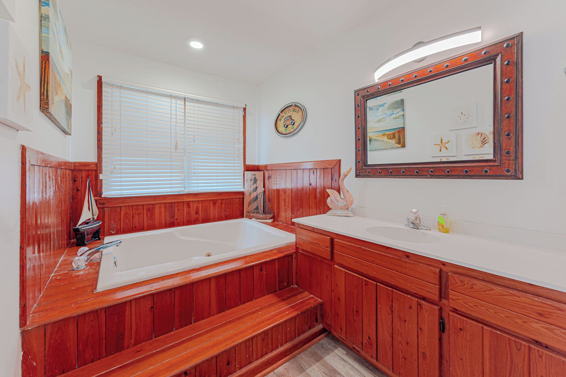 Un bagno con un mobile contenitore in legno, uno specchio grande e una decorazione a tema nautico.