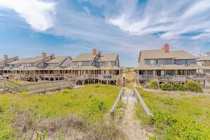 A beachfront property with multiple wooden structures, each featuring a balcony and a deck. - JL#201 | SIX - Classic Nags Head Oceanfront home with Hot Tub (Nags Head)