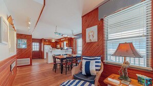 Een gezellige kamer met houten inrichting, een eethoek met stoelen, een tafel en een lamp.