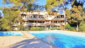 Un immeuble à plusieurs étages avec une piscine devant.
