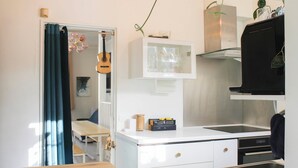 Una cocina compacta con una mesa de madera, armarios blancos, horno integrado y un lavamanos de acero inoxidable.