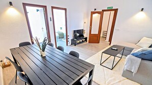 Una sala de estar moderna con una mesa de comedor de madera, sofá y mueble para la televisión.