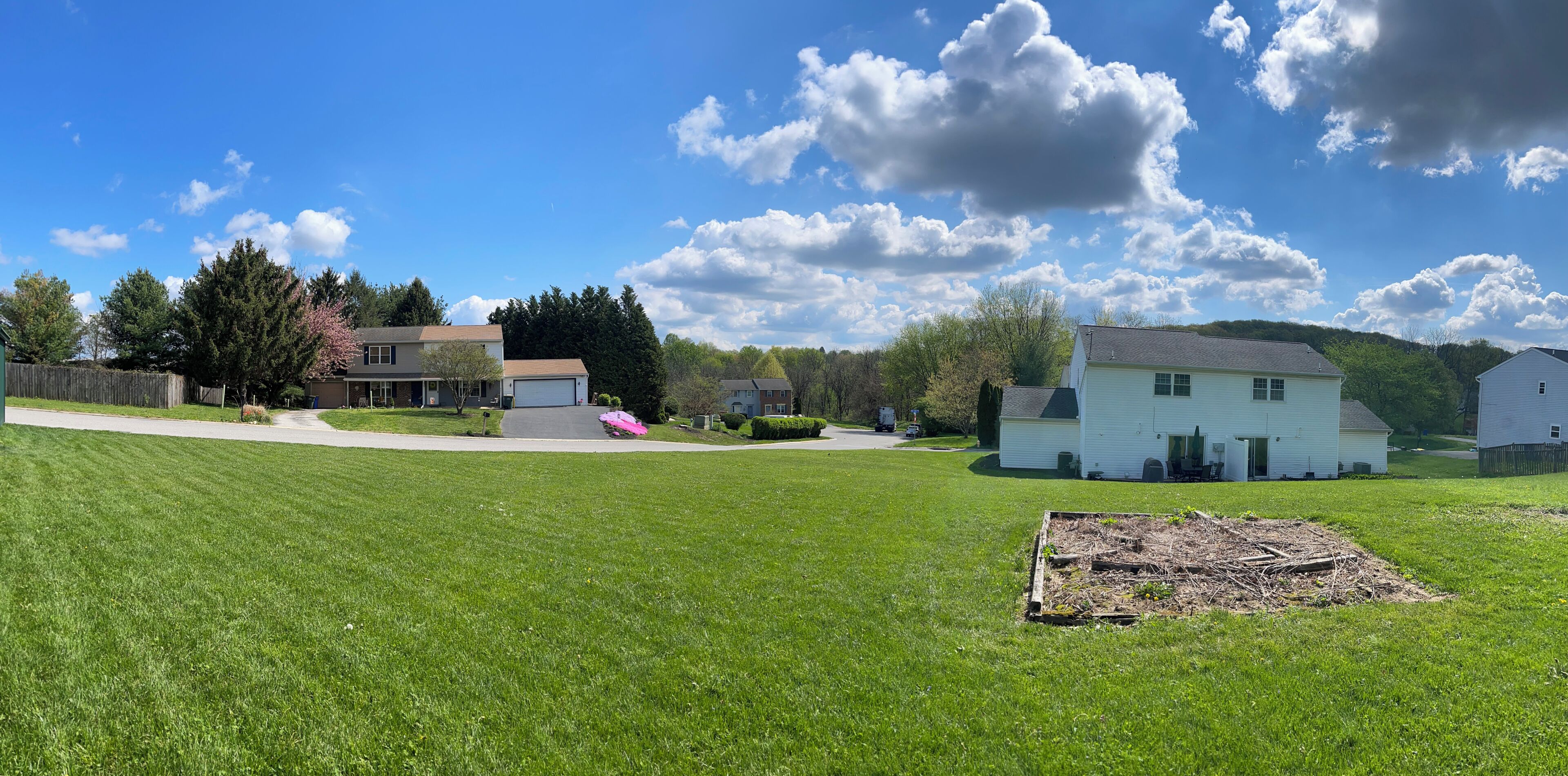 A residential area with houses, a grassy lawn, and a clear sky.