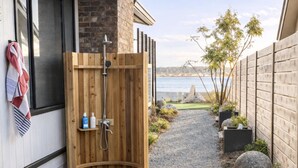A wooden sauna with a shower, a towel rack, and a view of the sea. - Beachfront I Tiki lounge | Pool table | Pinball I Mini Golf (Langley)