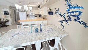 Een moderne keuken met witte kasten, een houten aanrecht en een eethoek met een witte tafel en stoelen.
