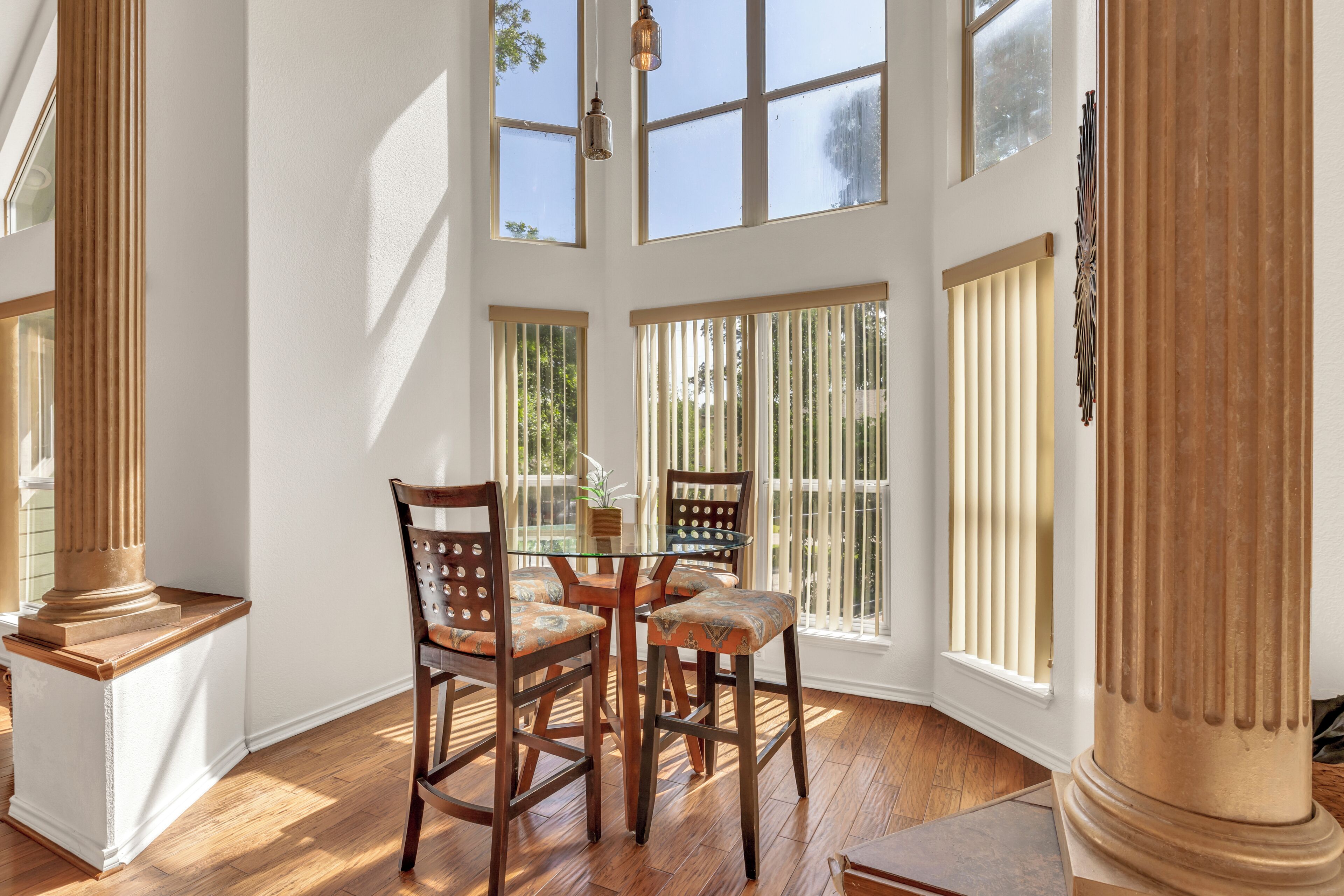 A dining area with a table and chairs, large windows, and a column.