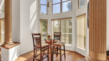 A dining area with a table and chairs, large windows, and a column.